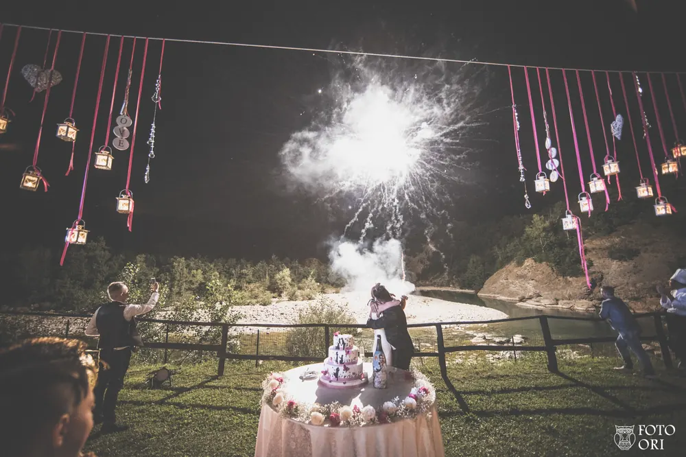 Taglio della torta nuziale con fuochi d'artificio sul fiume